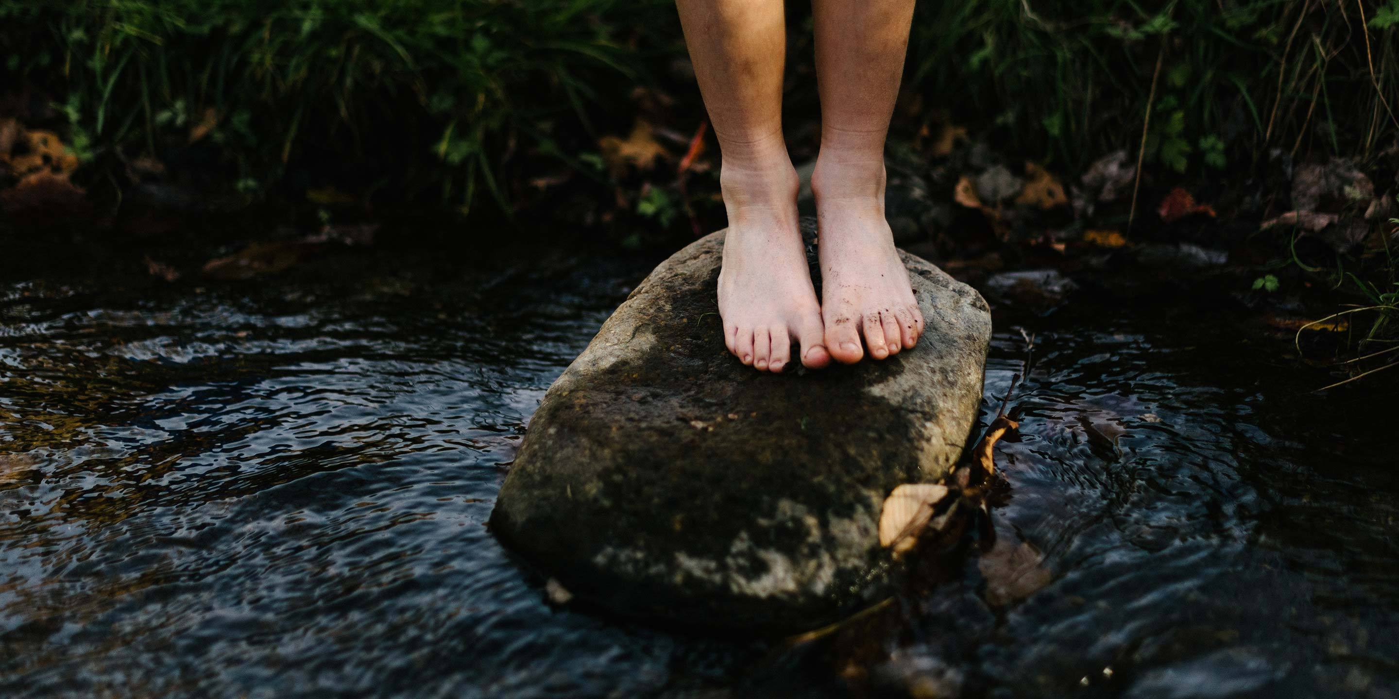 person standing on a rock in a stream